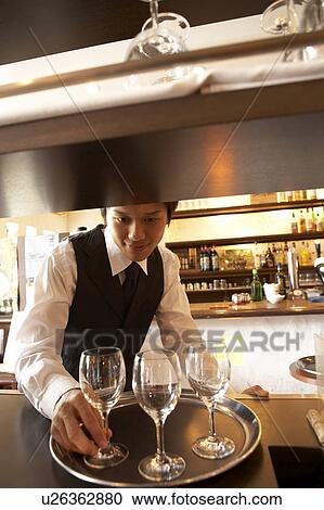 Stock Image - Waiter putting glasses on tray. Fotosearch