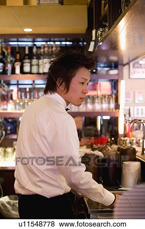 Stock Photo - Waiter standing behind bar counter. Fotosearch