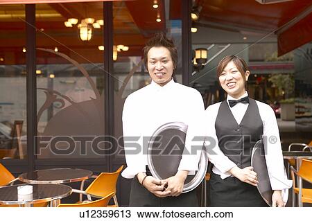 Stock Image - Waiters standing in front of coffee shop. Fotosearch