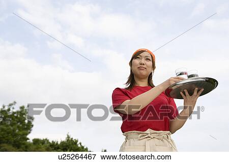 Stock Photo - Waitress carrying drinks on tray. Fotosearch