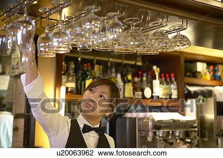 Stock Image - Waitress taking glass from shelf. Fotosearch