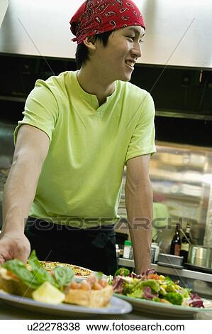 Stock Photo - Young man working in kitchen. Fotosearch