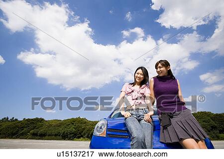 Stock Photo - Two young women leaning against car. Fotosearch