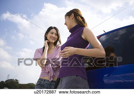 Stock Photo - Two young women leaning against car. Fotosearch