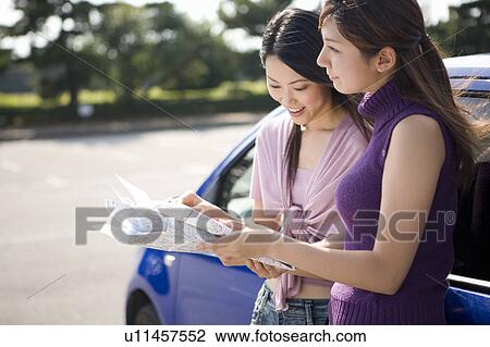 Stock Image - Two young women looking at map. Fotosearch