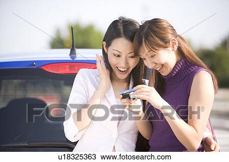 Stock Image - Two young women using digital camera. Fotosearch