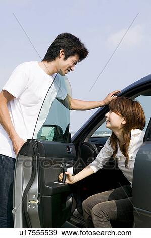 Stock Photo - Young couple getting out of car. Fotosearch