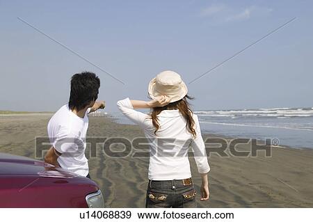 Stock Photo - Young couple standing on beach. Fotosearch