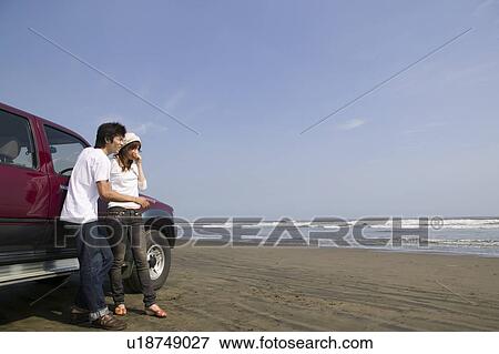 Stock Photo - Young couple standing on beach. Fotosearch