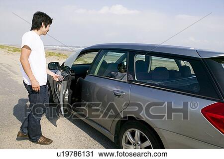 Young man opening car door View Large Photo Image Stock Image - Young man opening car door. Fotosearch