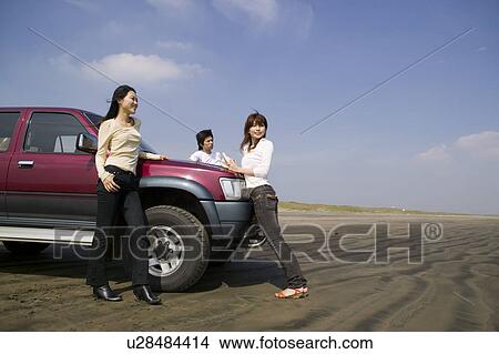 Young people leaning against car on beach View Large Photo Image Picture - Young people leaning against car on beach. Fotosearch