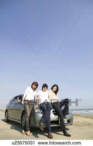 Young people leaning against car on beach View Large Photo Image Stock Image - Young people leaning against car on beach. Fotosearch