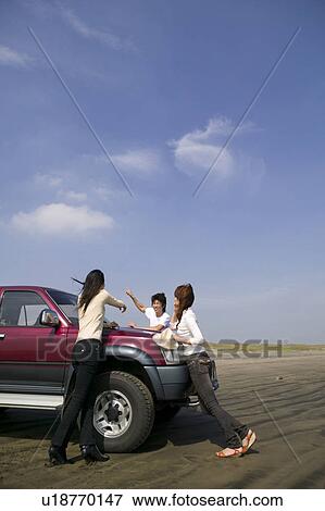Young people leaning against car on beach View Large Photo Image Stock Photo - Young people leaning against car on beach. Fotosearch