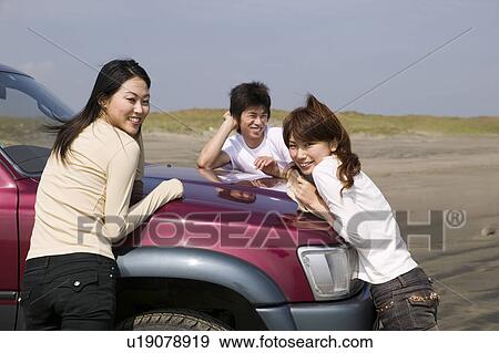 Young people leaning against car on beach View Large Photo Image Stock Photo - Young people leaning against car on beach. Fotosearch