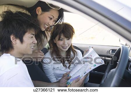 Stock Image - Young people looking at map. Fotosearch