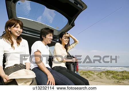 Young people sitting on rear of car View Large Photo Image Picture - Young people sitting on rear of car. Fotosearch