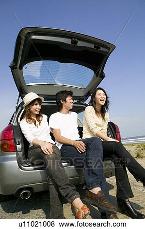 Young people sitting on rear of car View Large Photo Image Stock Photo - Young people sitting on rear of car. Fotosearch