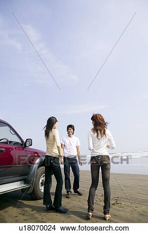 Picture - Young people standing on beach. Fotosearch