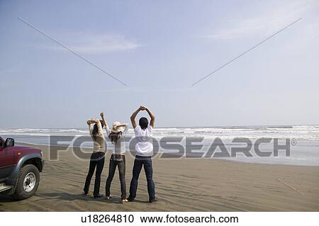 Young people standing on beach View Large Photo Image Stock Image - Young people standing on beach. Fotosearch