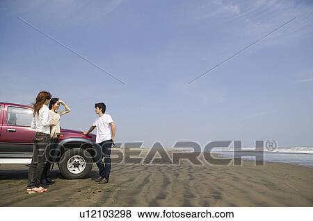Stock Photo - Young people standing on beach. Fotosearch