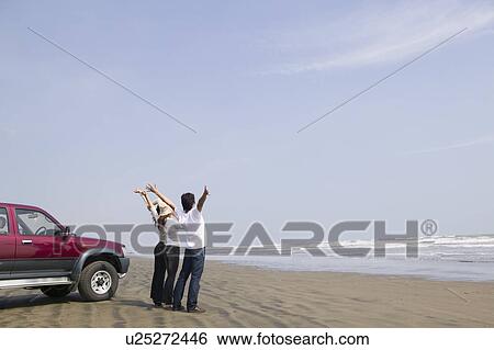 Stock Photograph - Young people standing on beach. Fotosearch