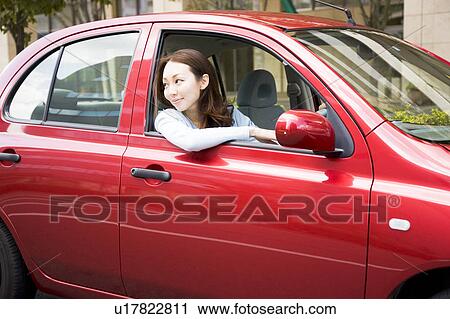 Stock Image - Young woman driving car. Fotosearch