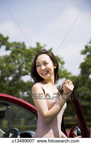 Stock Photo - Young woman getting out of car. Fotosearch