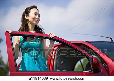 Young woman leaning against open door of car View Large Photo Image Stock Photo - Young woman leaning against open door of car. Fotosearch