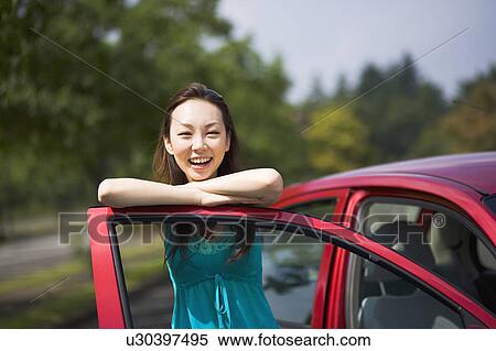 Young woman leaning against open door of car View Large Photo Image Stock Photography - Young woman leaning against open door of car. Fotosearch