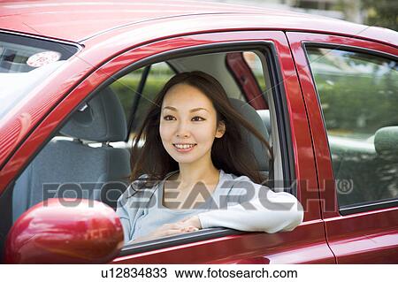 Stock Image - Young woman sitting in passenger seat in car. Fotosearch