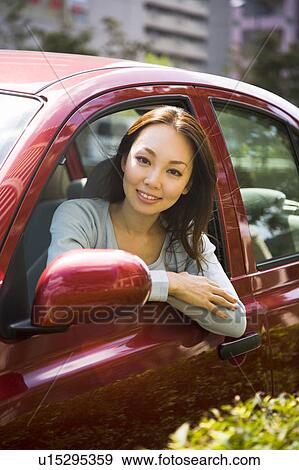Stock Photo - Young woman sitting in passenger seat in car. Fotosearch