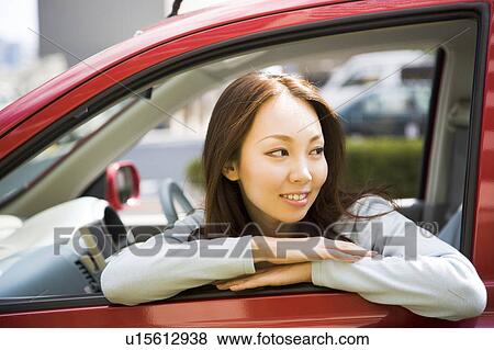 Stock Photo - Young woman sitting in passenger seat in car. Fotosearch
