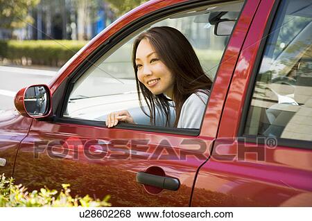 Stock Photo - Young woman sitting in passenger seat in car. Fotosearch