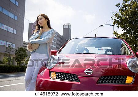 Young woman standing beside car View Large Photo Image Stock Image - Young woman standing beside car. Fotosearch