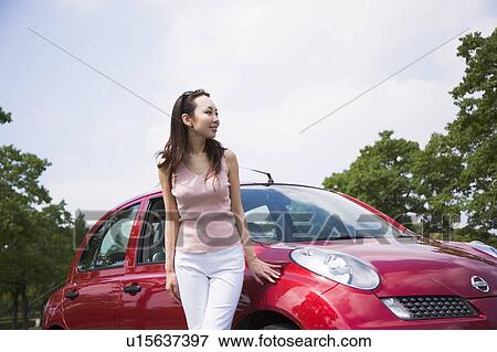 Stock Photo - Young woman standing beside car. Fotosearch