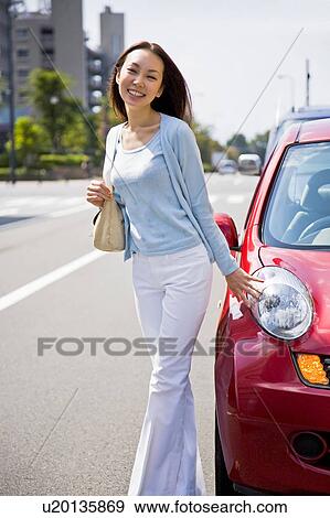 Young woman standing beside car View Large Photo Image Stock Photo - Young woman standing beside car. Fotosearch