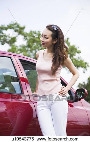 Stock Photography - Young woman standing beside car. Fotosearch