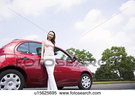 Stock Photography - Young woman standing beside car. Fotosearch