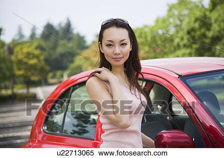 Young woman standing beside car View Large Photo Image Stock Photography - Young woman standing beside car. Fotosearch