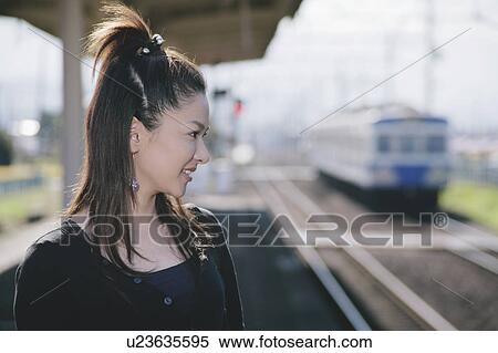 Stock Photography - Profile of young woman standing on train platform. Fotosearch