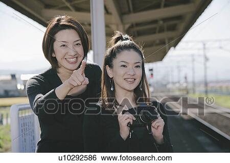 Stock Photograph - Two young women, one with camera. Fotosearch