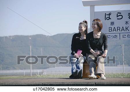 Two young women sitting on suitcase on train platform View Large Photo Image Stock Photography - Two young women sitting on suitcase on train platform. Fotosearch