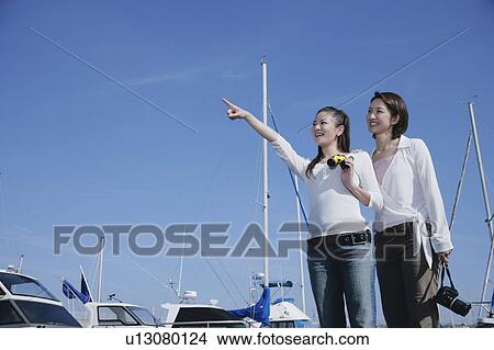 Picture - Two young women standing in marina. Fotosearch