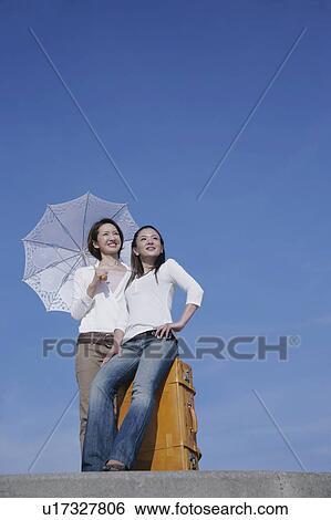 Two young women standing on breakwater View Large Photo Image Stock Photograph - Two young women standing on breakwater. Fotosearch