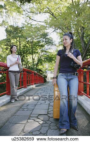 Stock Photo - Two young women standing on bridge. Fotosearch