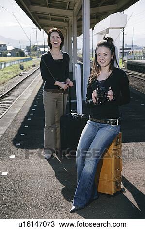 Stock Image - Two young women standing on train platform. Fotosearch