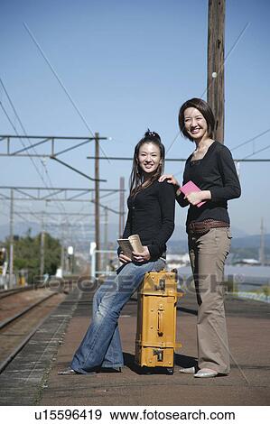 Two young women standing on train platform View Large Photo Image Stock Photo - Two young women standing on train platform. Fotosearch