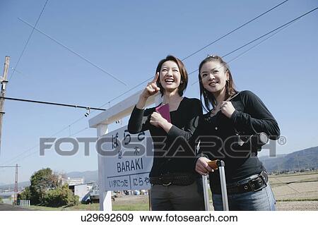 Two young women standing on train platform View Large Photo Image Stock Photo - Two young women standing on train platform. Fotosearch