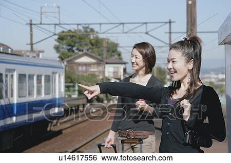 Stock Photograph - Two young women standing on train platform. Fotosearch