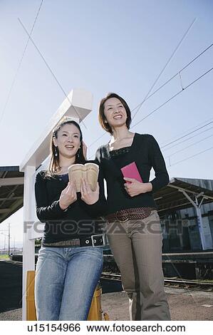 Two young women standing on train platform View Large Photo Image Stock Photograph - Two young women standing on train platform. Fotosearch